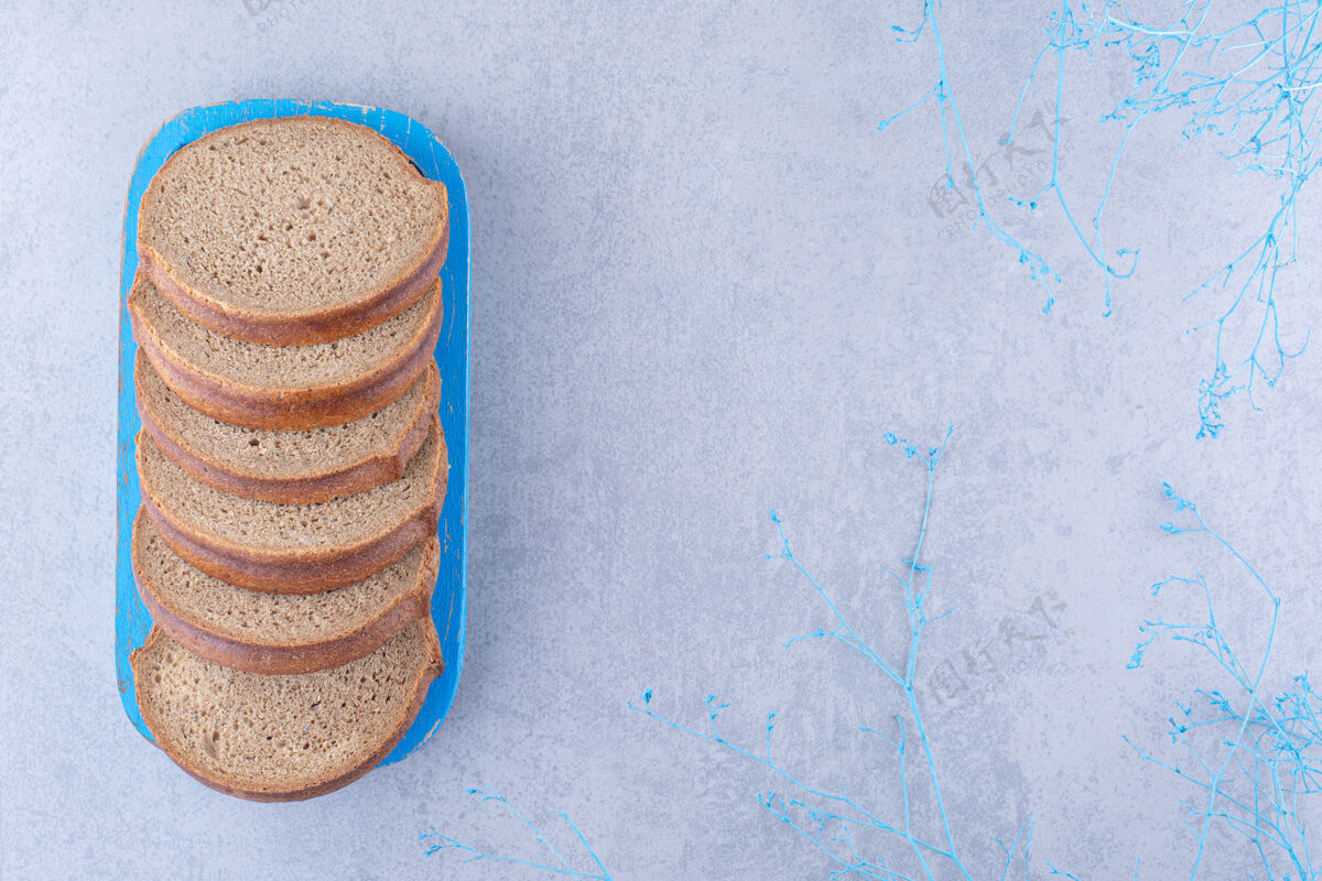 营养把棕色面包片放在大理石表面的蓝色盘子里烘焙食品馒头酵母