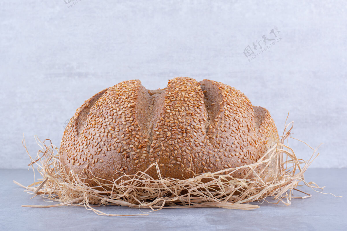 面包面包放在大理石表面的稻草堆上稻草面包烘焙食品