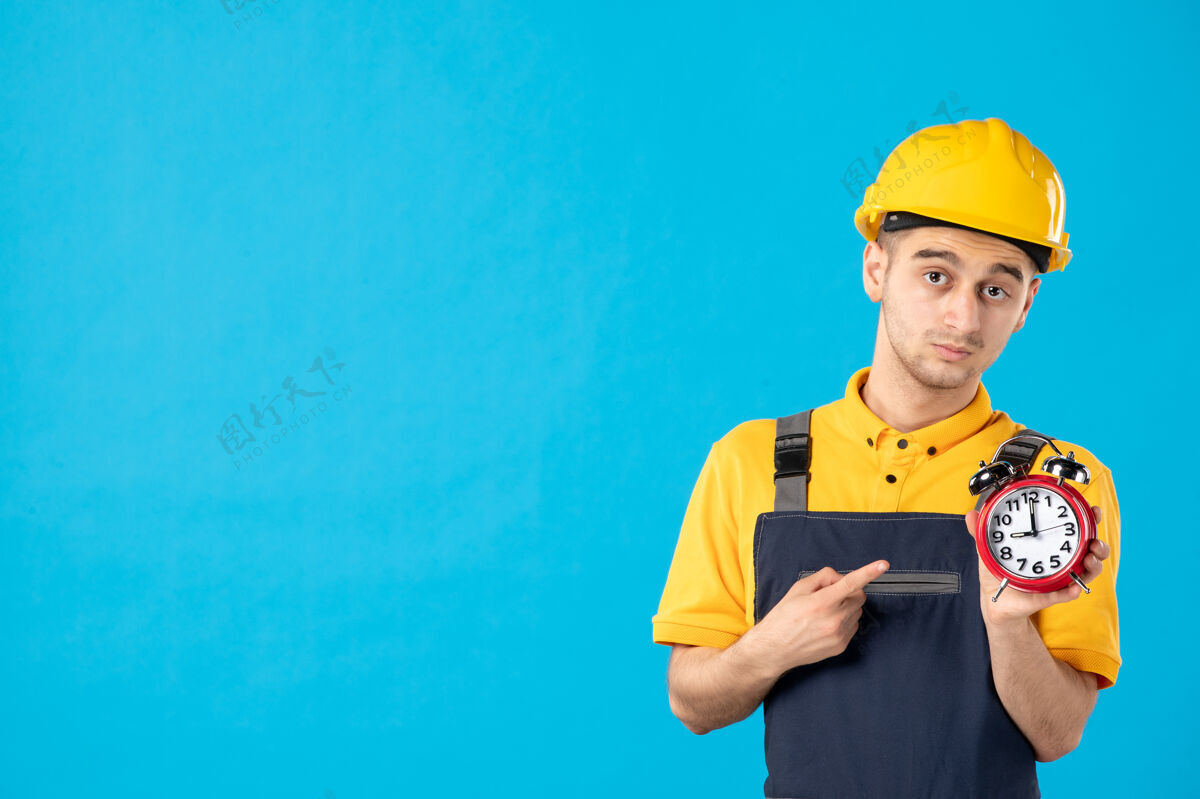 施工身着黄色制服 蓝色时钟的严肃男工人的正面图职业头盔表面