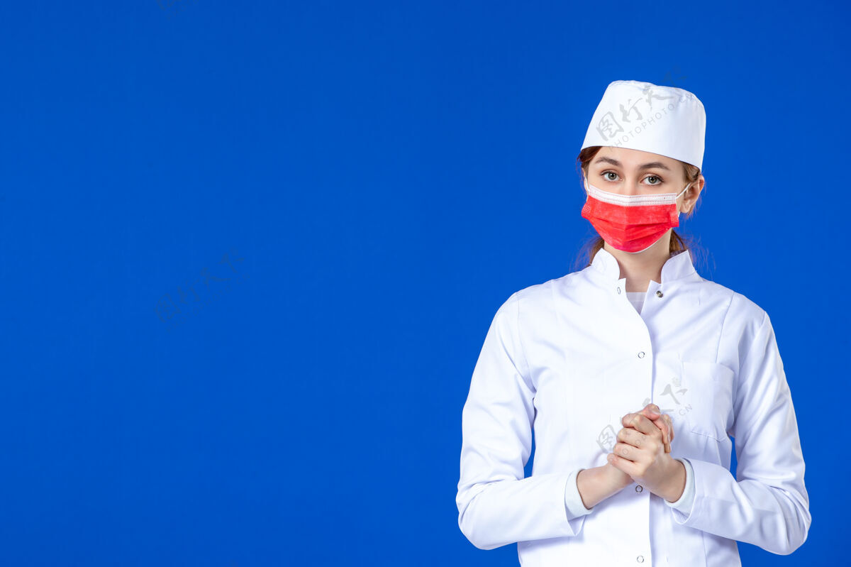职业压力重重的年轻护士的正视图 身着医疗服 蓝色面罩上戴着红色面罩疾病衣服病毒