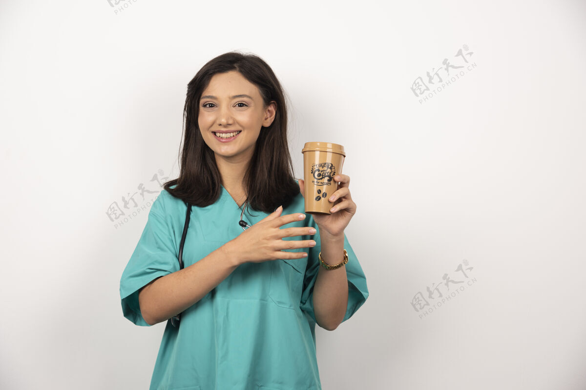 女性微笑的医生拿着听诊器 拿着一杯白底咖啡职业医生持有