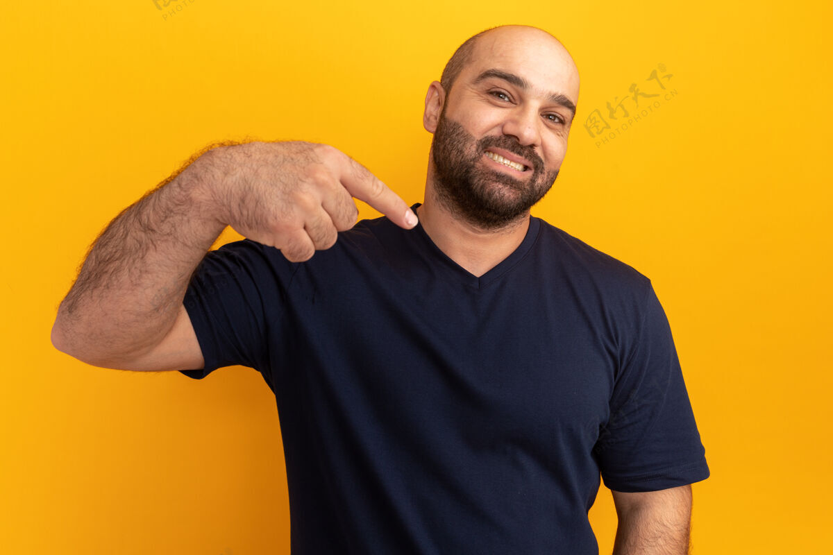 指点一个穿着海军t恤的大胡子男人自信地微笑着 用食指指着站在橙色墙上的自己手势站立表情