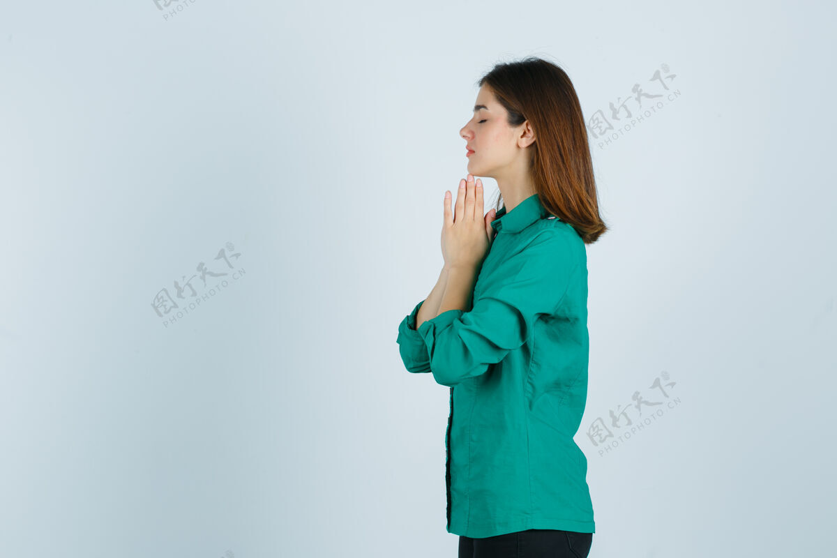冥想美丽的年轻女士手牵手在祈祷的姿态在绿色衬衫 看起来充满希望教会祈祷太阳