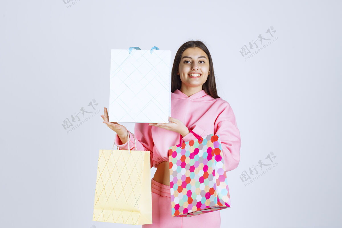 模特带着五颜六色购物袋的女孩看起来很开心很满意服装年轻女人