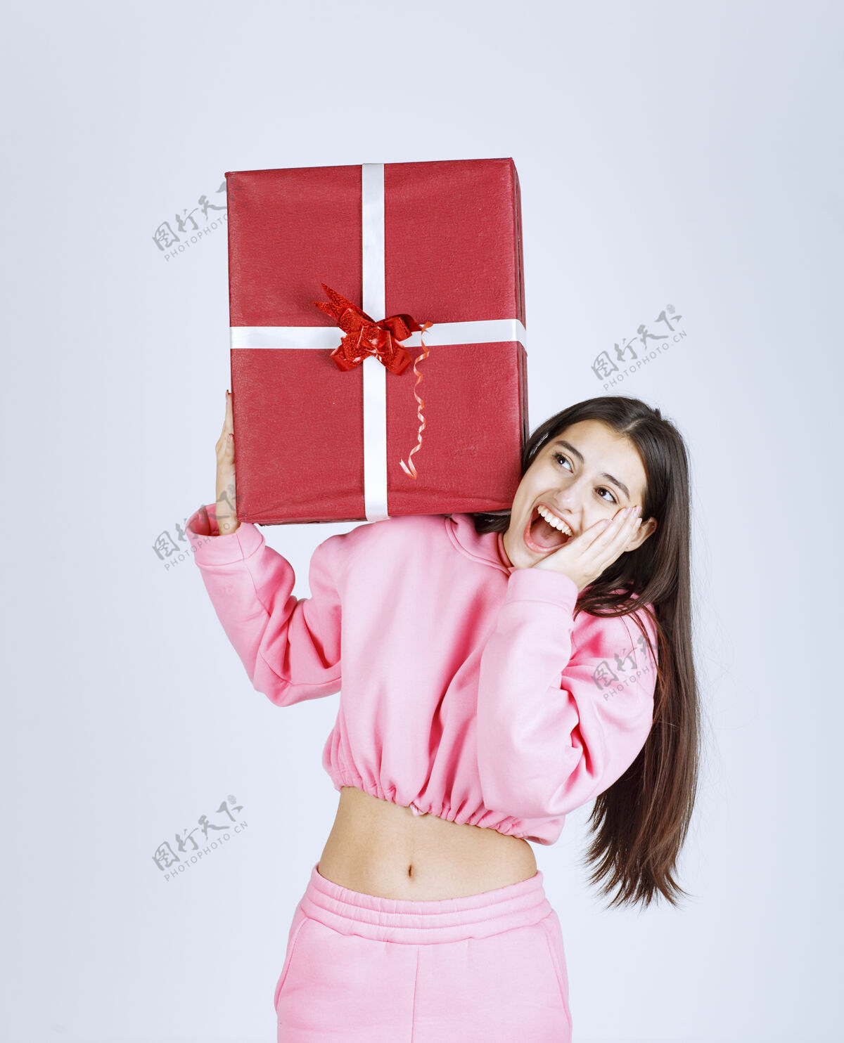乐趣穿着粉色睡衣的女孩头上戴着一个红色的大礼盒庆祝姿势年轻人
