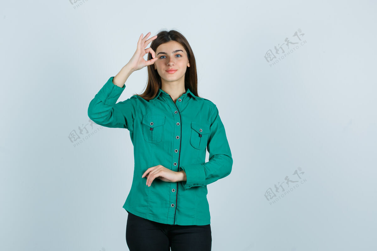 享受身着绿色衬衫的年轻女性展现出良好的姿态 看上去很欢快 正面视图庆祝正面冷淡