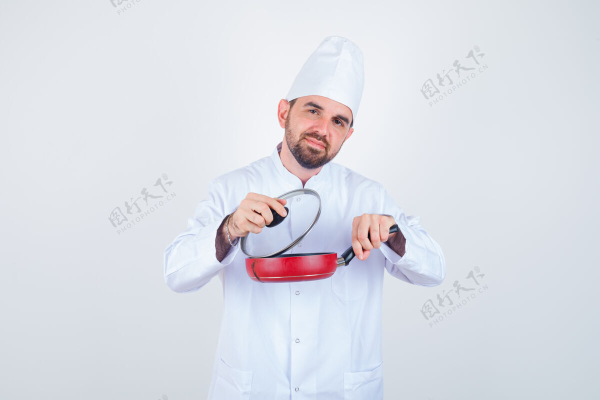 专业年轻的男厨师正在从煎锅上取下锅盖 身穿白色制服 看上去很好奇 正前方视图杂务好奇薯条