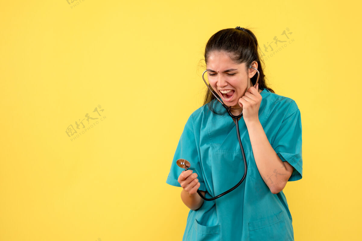 医学正面图：女医生手持听诊器站在黄色背景上大声喊叫护士医院喊着