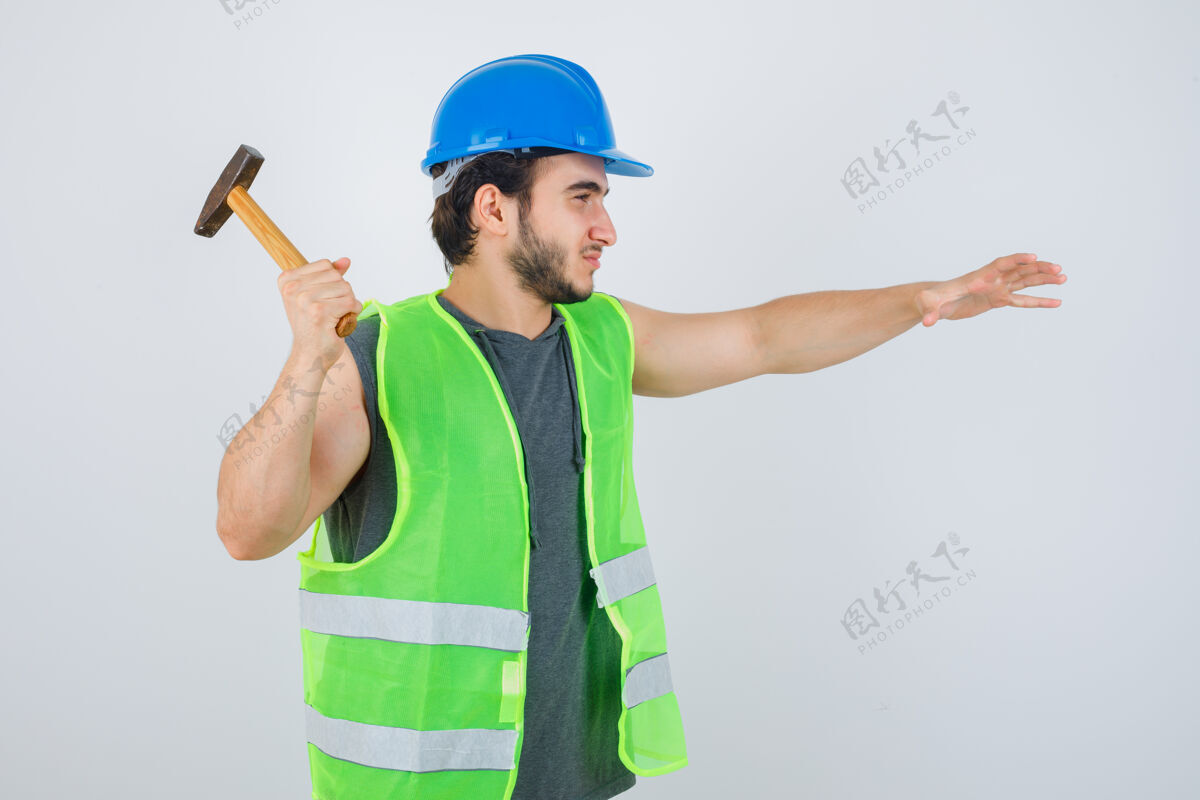 休闲年轻的建筑工人穿着工作服准备使用锤子 看上去很自信 正面视图人时尚人