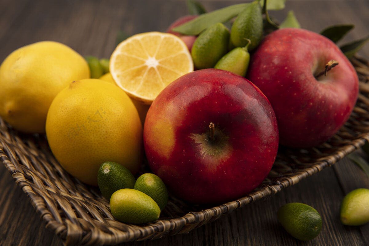 饮食俯瞰富含维生素的水果 如苹果 柠檬和金盏花在柳条托盘上的木制表面苹果人美味