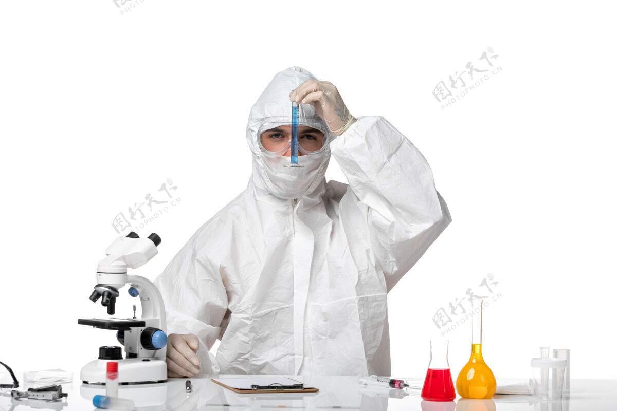 外套正面图：男医生穿着防护服 戴着面罩 因为covid拿着蓝色溶液的烧瓶 在浅白色的空间里病毒到期保温瓶