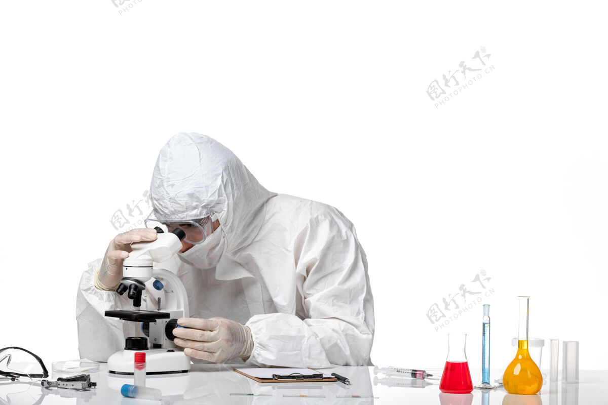 口罩前视图：男医生穿着防护服 戴着面罩 在空白处使用显微镜男性使用男性医生