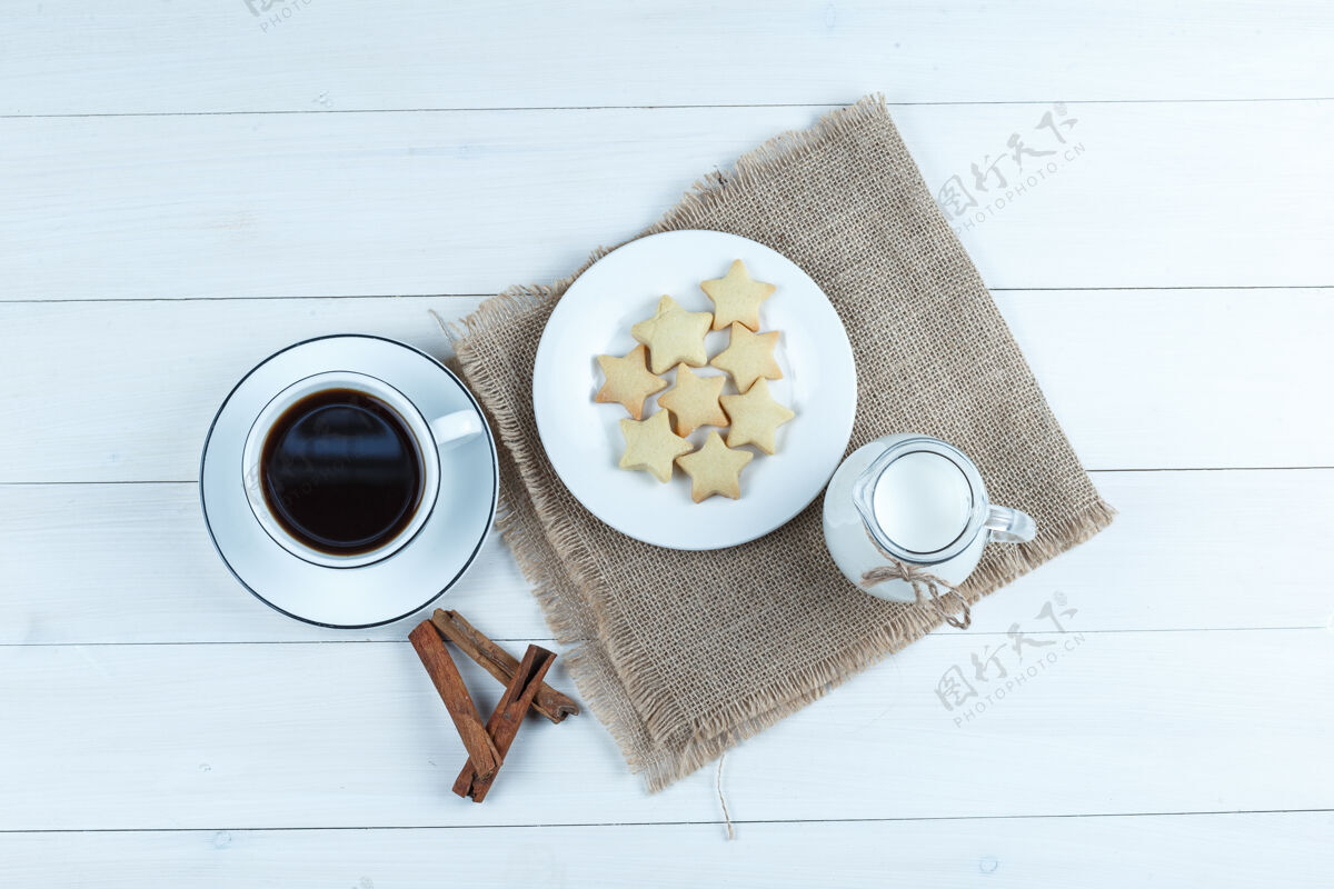 乡村的咖啡在一个杯子里 饼干 肉桂棒 牛奶顶视图在木头和一块布袋背景上卡布奇诺棒豆子