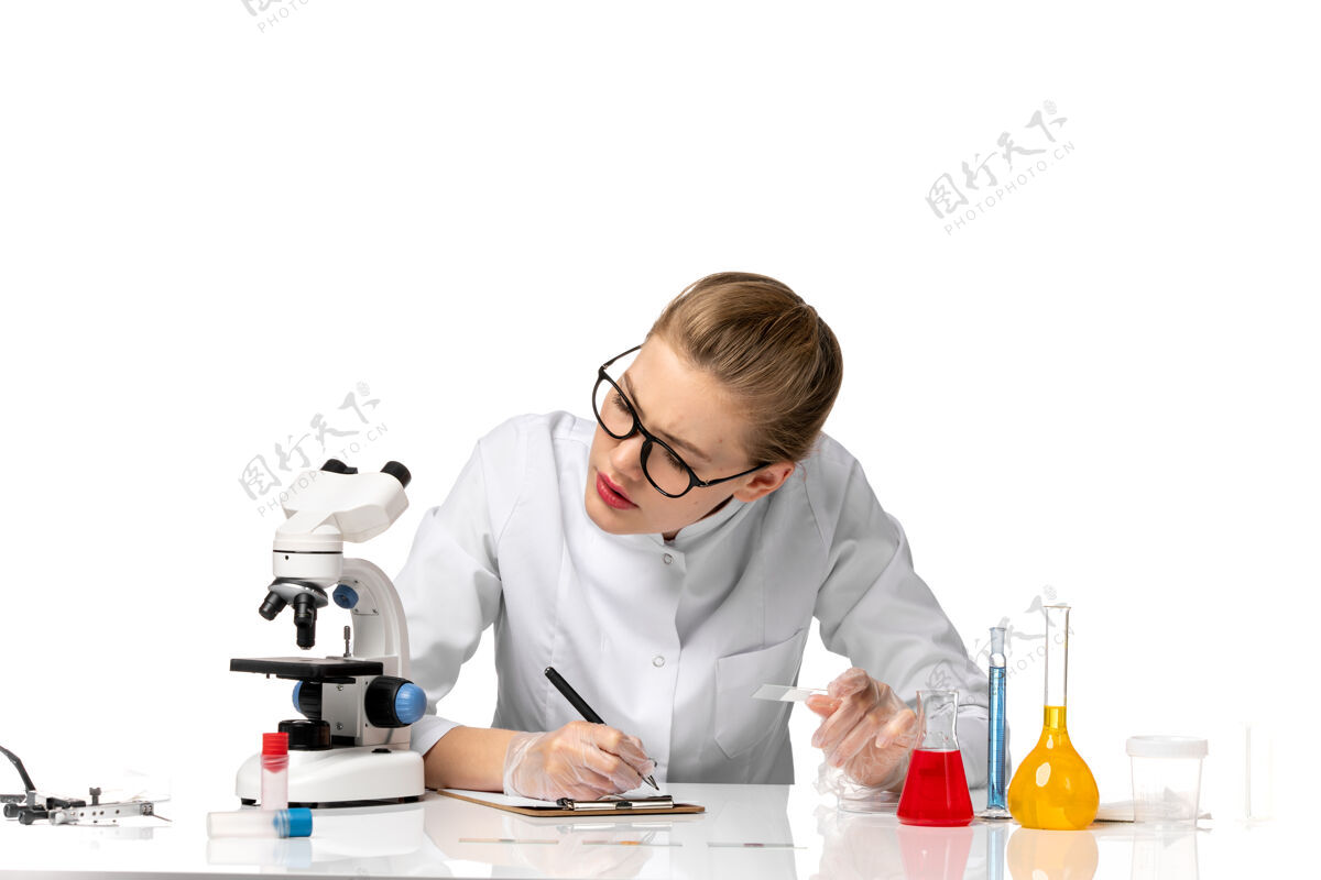 女医生前视图穿着白色医疗服的女医生在空白处写笔记办公室职业病毒