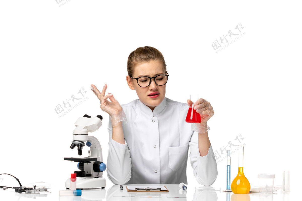 手套正面图：穿着白色医疗服的女医生 戴着手套 在白色桌子上拿着装有溶液的烧瓶工作流行病套装