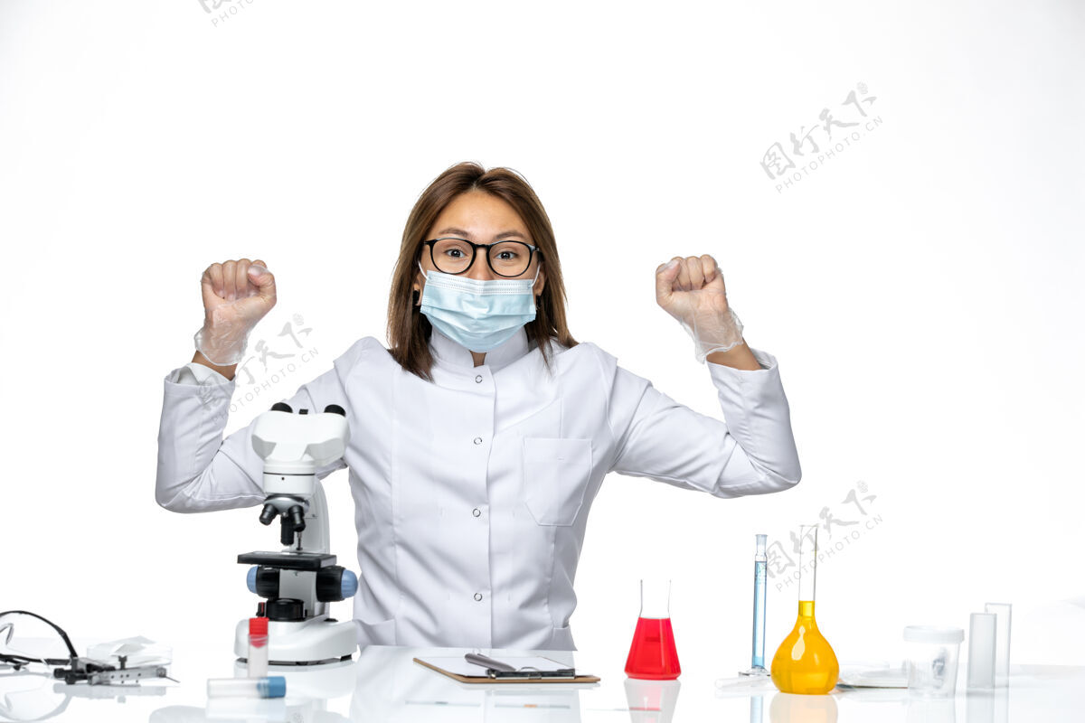 专业人员在白色办公桌上使用显微镜 看到穿着白色医疗服 戴着口罩的女医生药品到期实验室外套