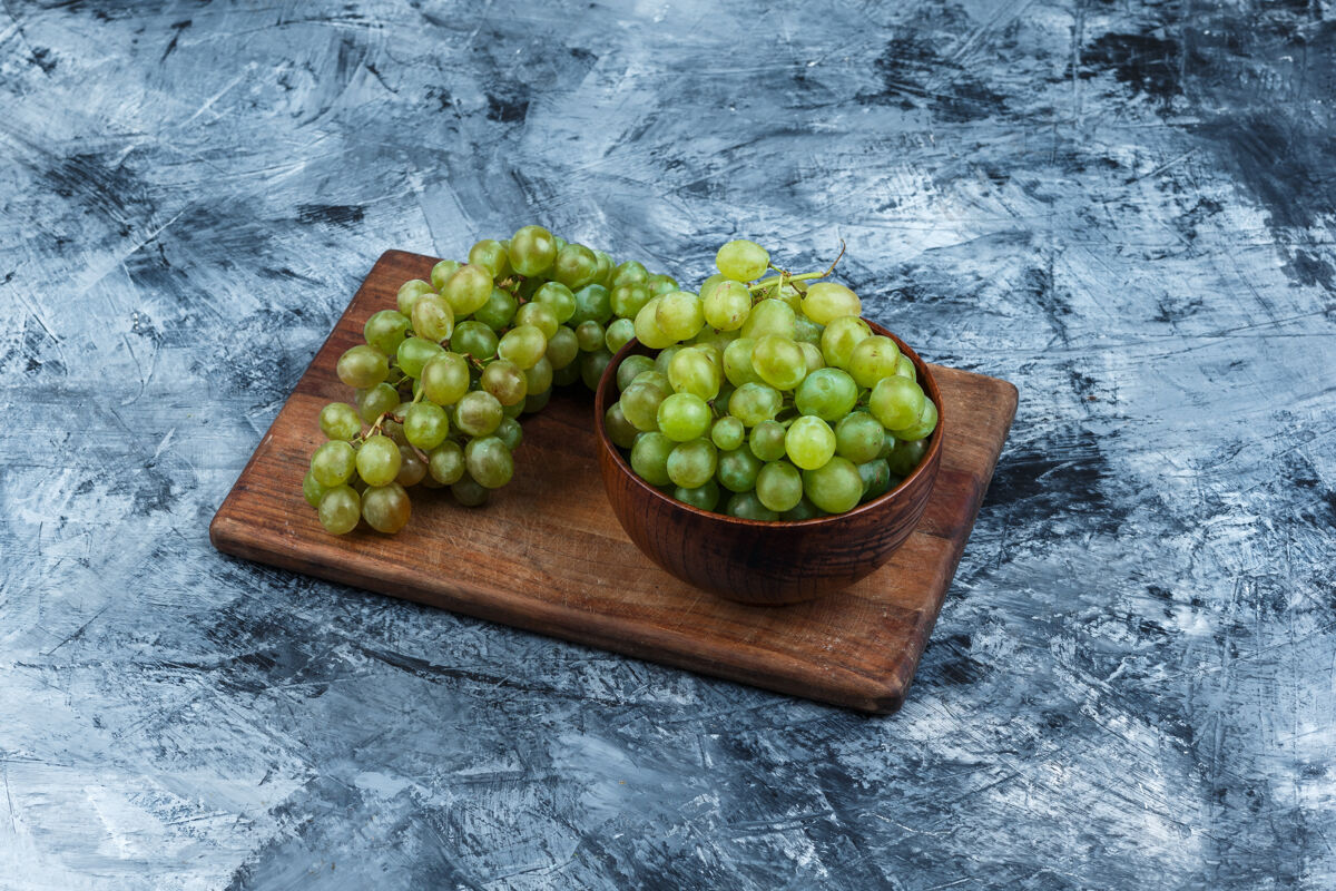 树枝一碗葡萄放在深蓝色大理石背景的砧板上高角度视图路径食物多汁