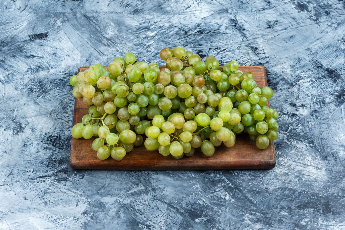果皮绿色葡萄在灰色和砧板背景上水平大饮食有机
