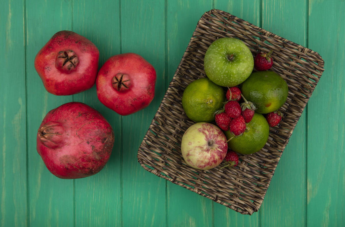 篮子顶视图石榴与橘子苹果和草莓在一个绿色的墙上篮子水果苹果观点