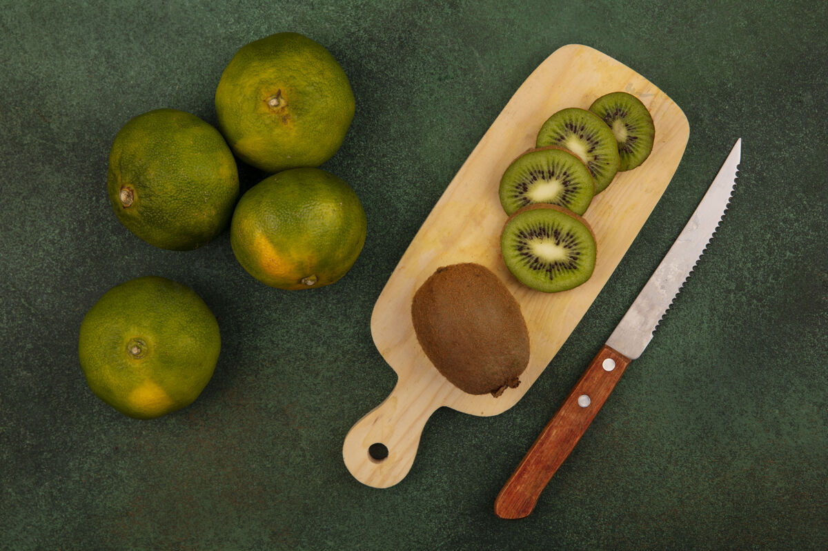板用刀在砧板上切猕猴桃片 在绿墙上切橘子切片橘子水果