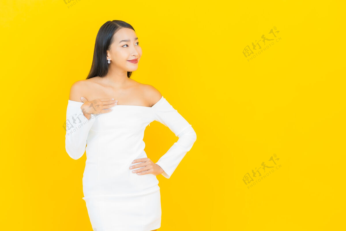 亚洲人美丽的亚洲年轻商业女性在黄色墙壁上穿着白色裙子微笑的画像可爱积极人