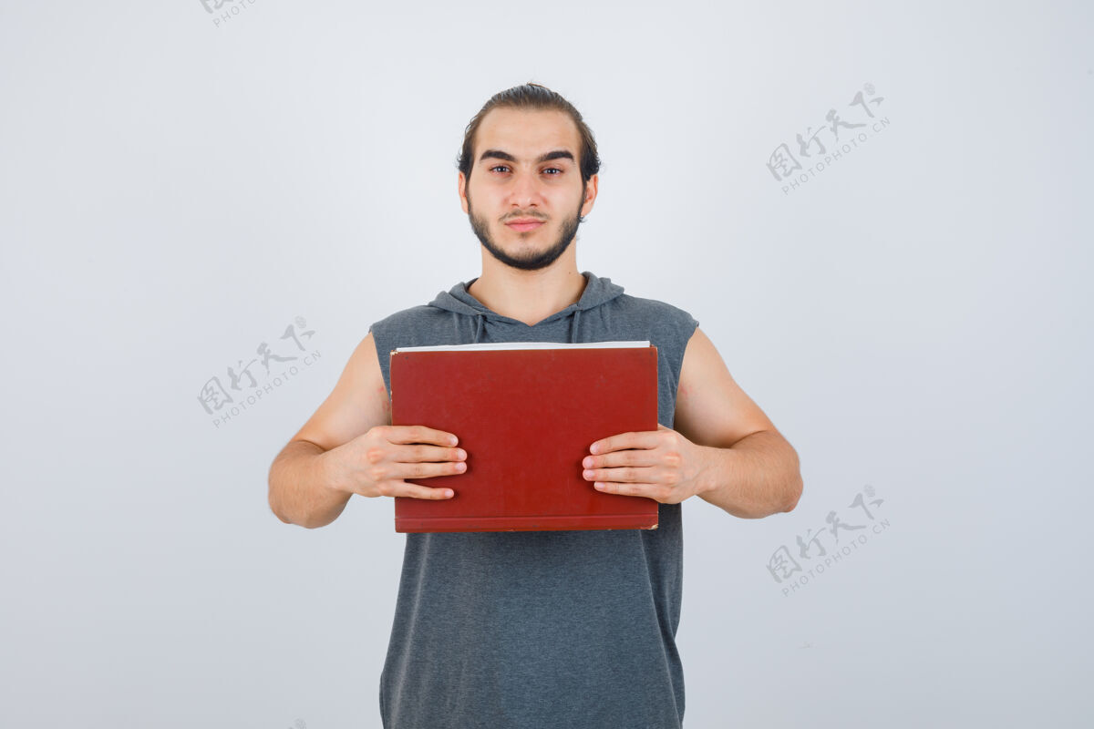 站立年轻的男子拿着一本书在他面前 穿着无袖连帽衫 看上去很严肃男人严肃成人