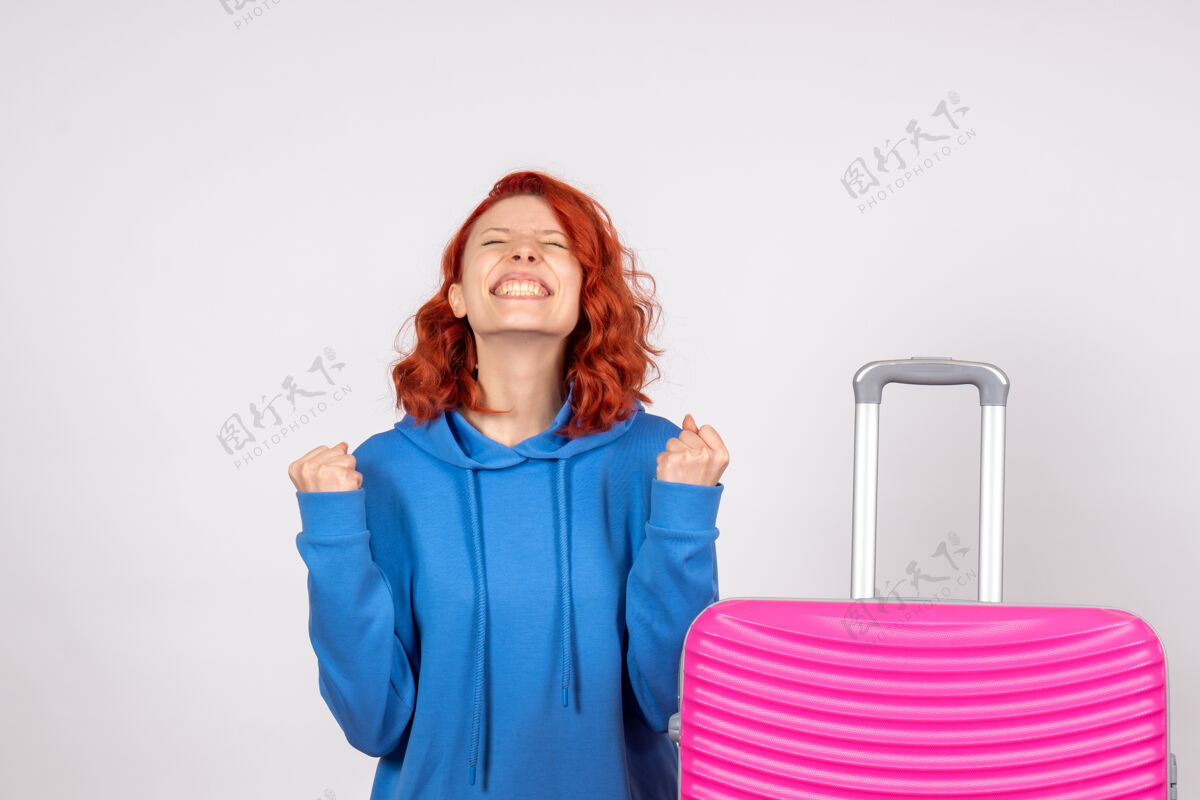 假期白色墙壁上 年轻的女性游客带着粉红色的包欢呼雀跃成人快乐肖像