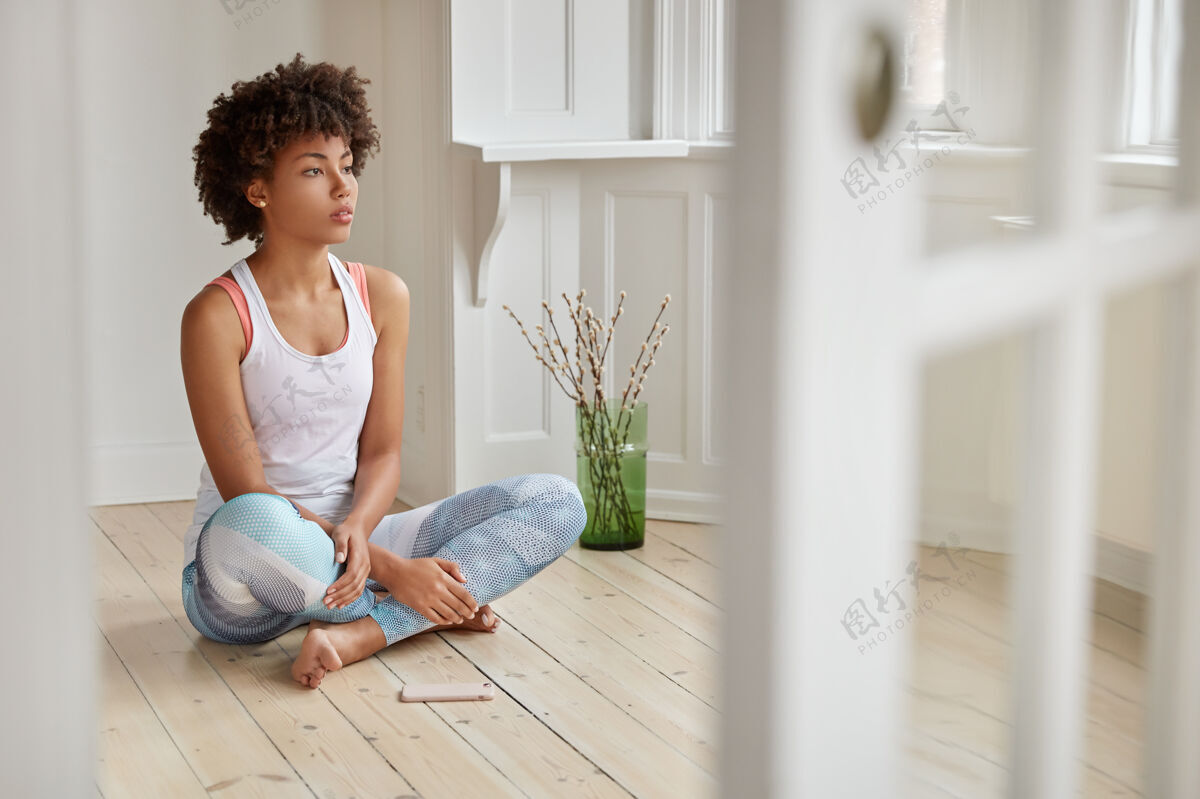 设备照片中的黑人女子盘腿坐在木地板上地板思想放松