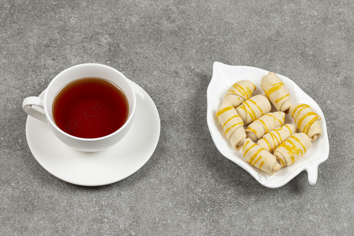 茶在大理石表面放上一盘饼干和一杯茶杯子黄油美味
