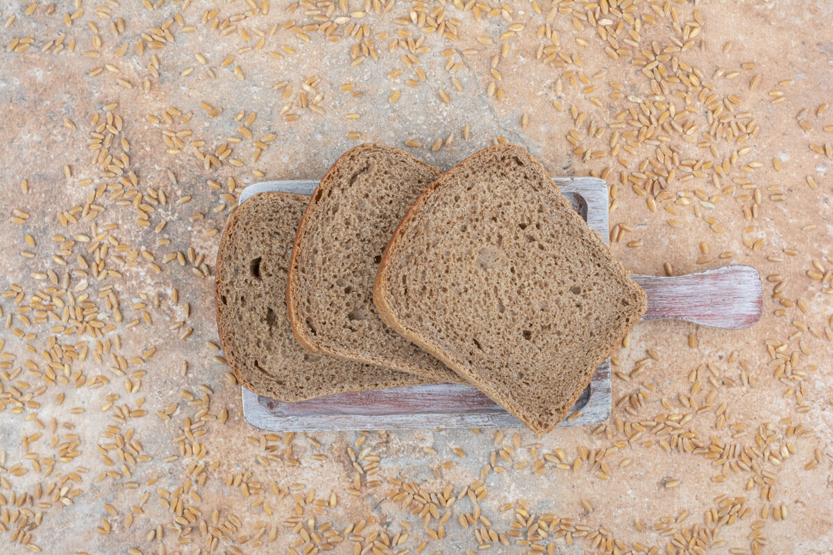 新鲜黑面包片和大麦粒在大理石表面切片美味面包房