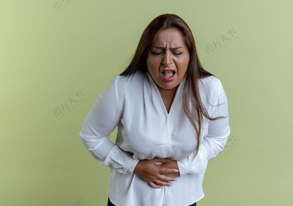 疼生病的白种中年妇女随便抓住疼痛的胃隔离在橄榄绿的墙上抓奥利弗女人