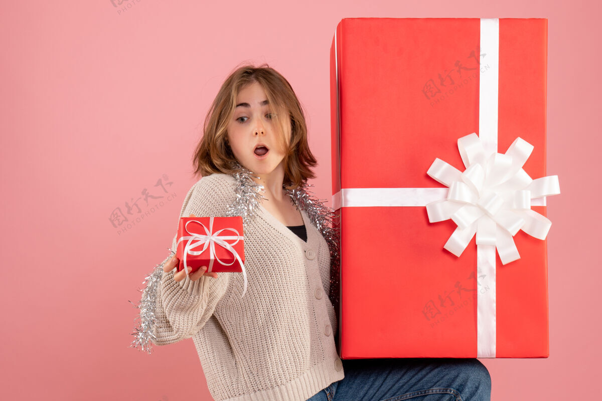 圣诞节年轻的女性拿着粉红色的圣诞礼物盒年轻的女性举行人们