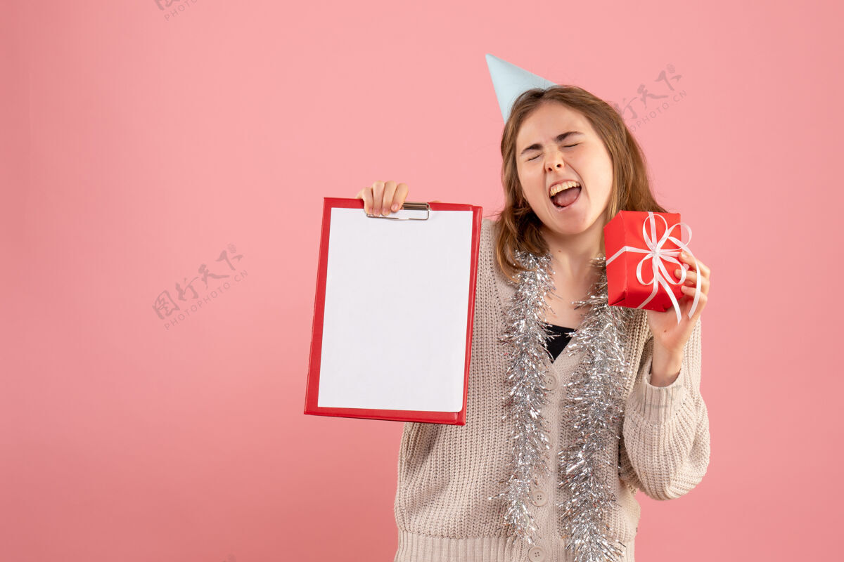 便条年轻的女性拿着小圣诞礼物和粉红色的纸条时尚人女士