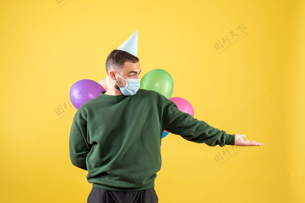 人正面图黄色背景上手持彩色气球的年轻男性年轻男性人衣服