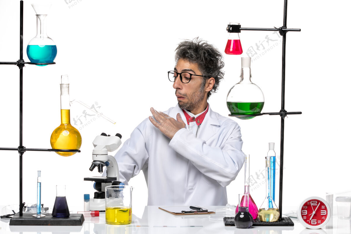 科学前视图穿着白色医疗服的中年化学家坐在那里用溶液清洗他的衣服实验室医疗实验室