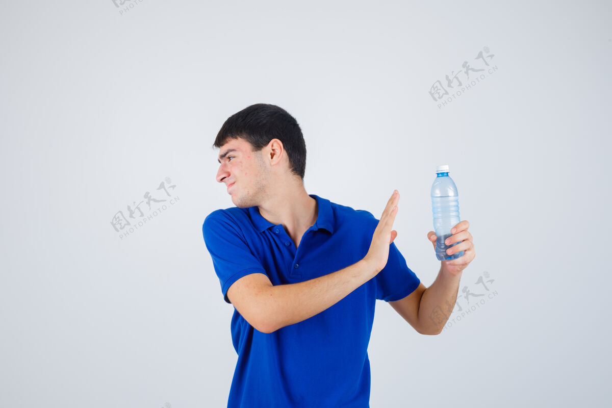 童年年轻人手里拿着塑料瓶 穿着t恤衫做着停车的手势 看上去很恼火前视图头不安英俊
