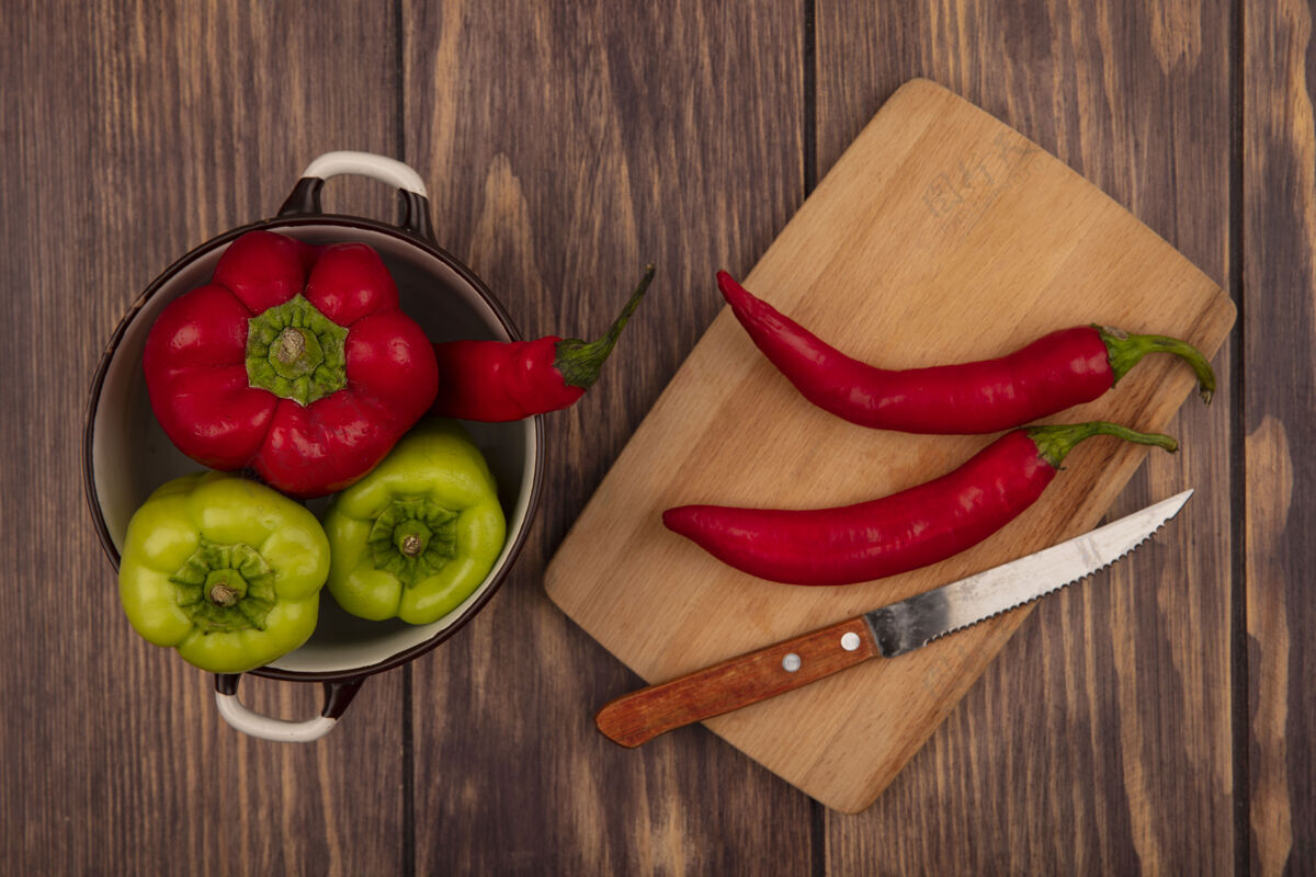 食物顶视图新鲜的甜椒放在一个碗上 辣椒放在木制的厨房板上 刀放在木制的墙上烹饪辣椒胡椒