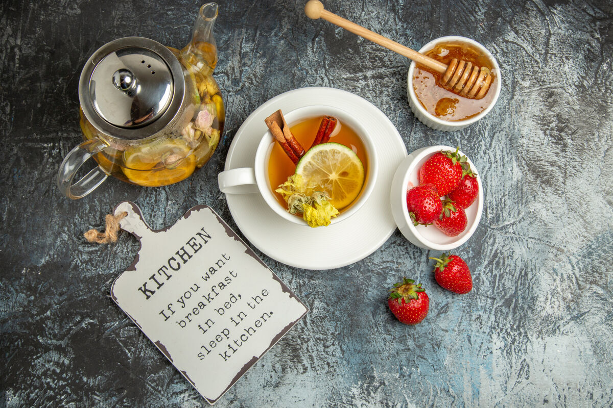 盘子顶视图一杯茶与草莓和蜂蜜在黑暗的表面水果茶浆果菜肴茶杯营养品