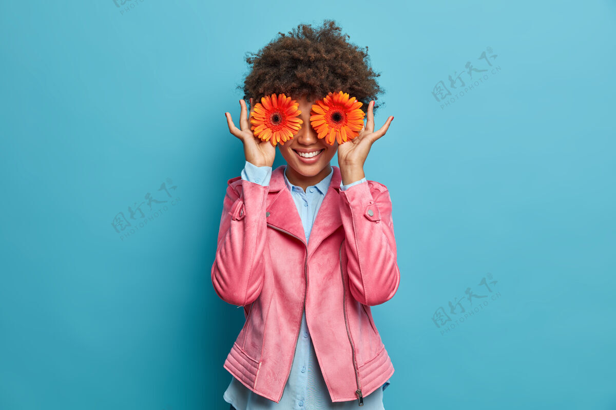 女性快乐微笑的女人用两个橘色的非洲菊掩面 喜欢花 表达快乐和喜悦快乐的花商要做漂亮的花束出售 在花店工作优雅非洲菊粉色