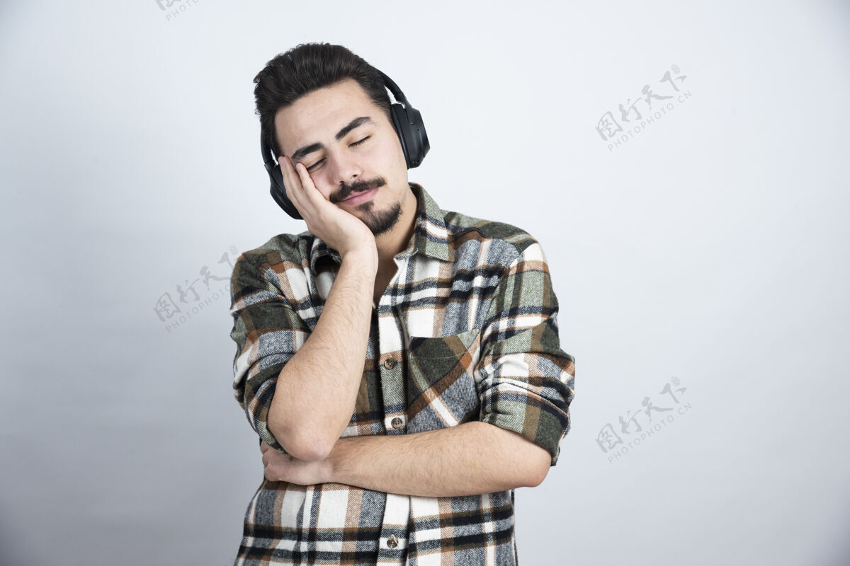 睡眠戴着耳机睡在白墙上的帅哥男人年轻声音