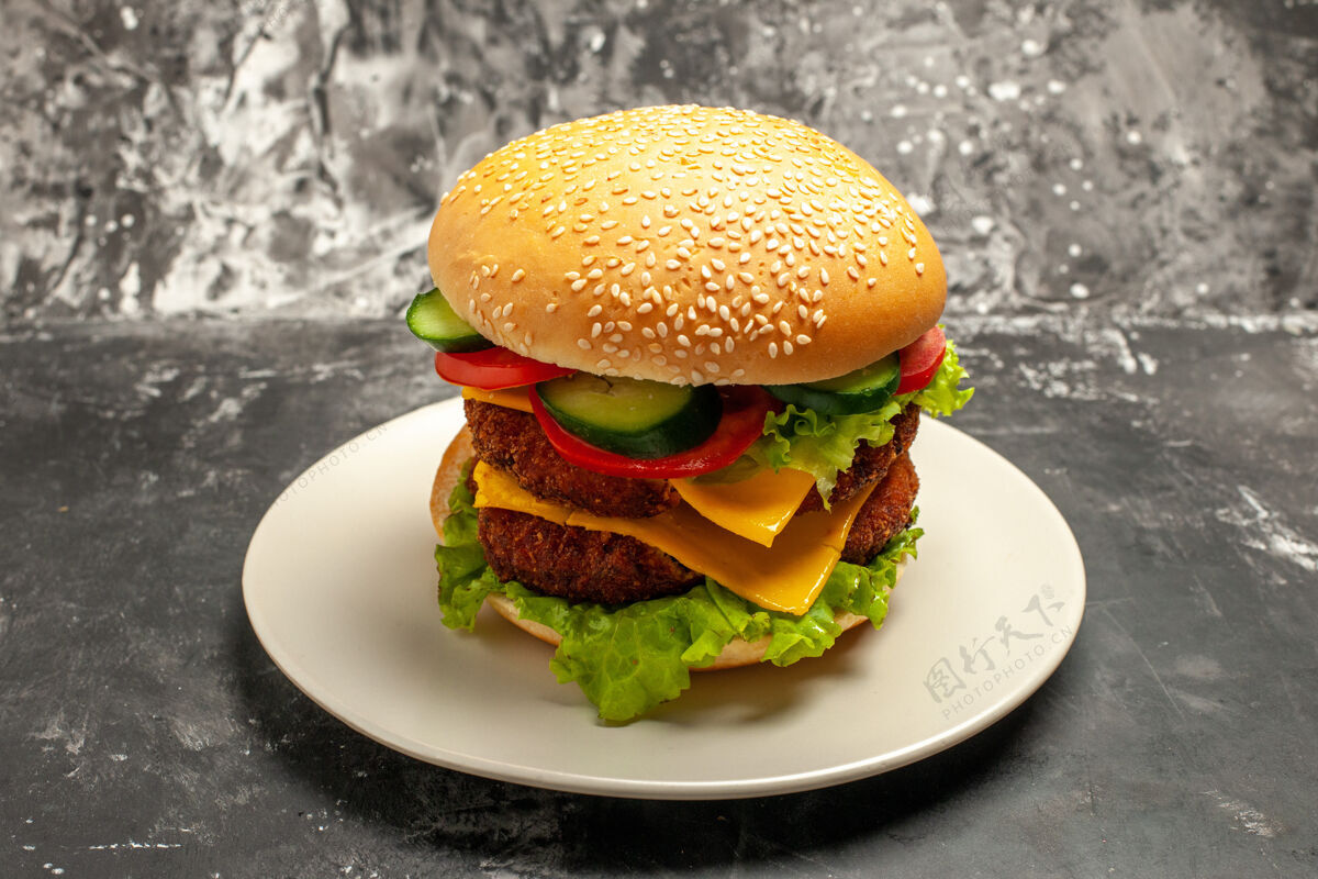 西红柿正面图美味的肉汉堡和蔬菜在黑暗的表面三明治快餐包面包肉生菜