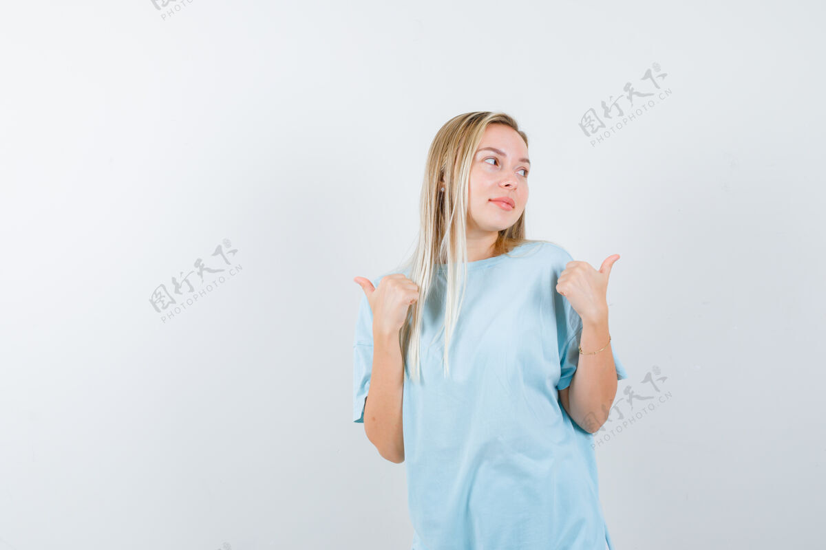 女性穿着蓝色t恤的金发女孩 拇指指向一边 看起来很开心 正前方时尚女人卷发