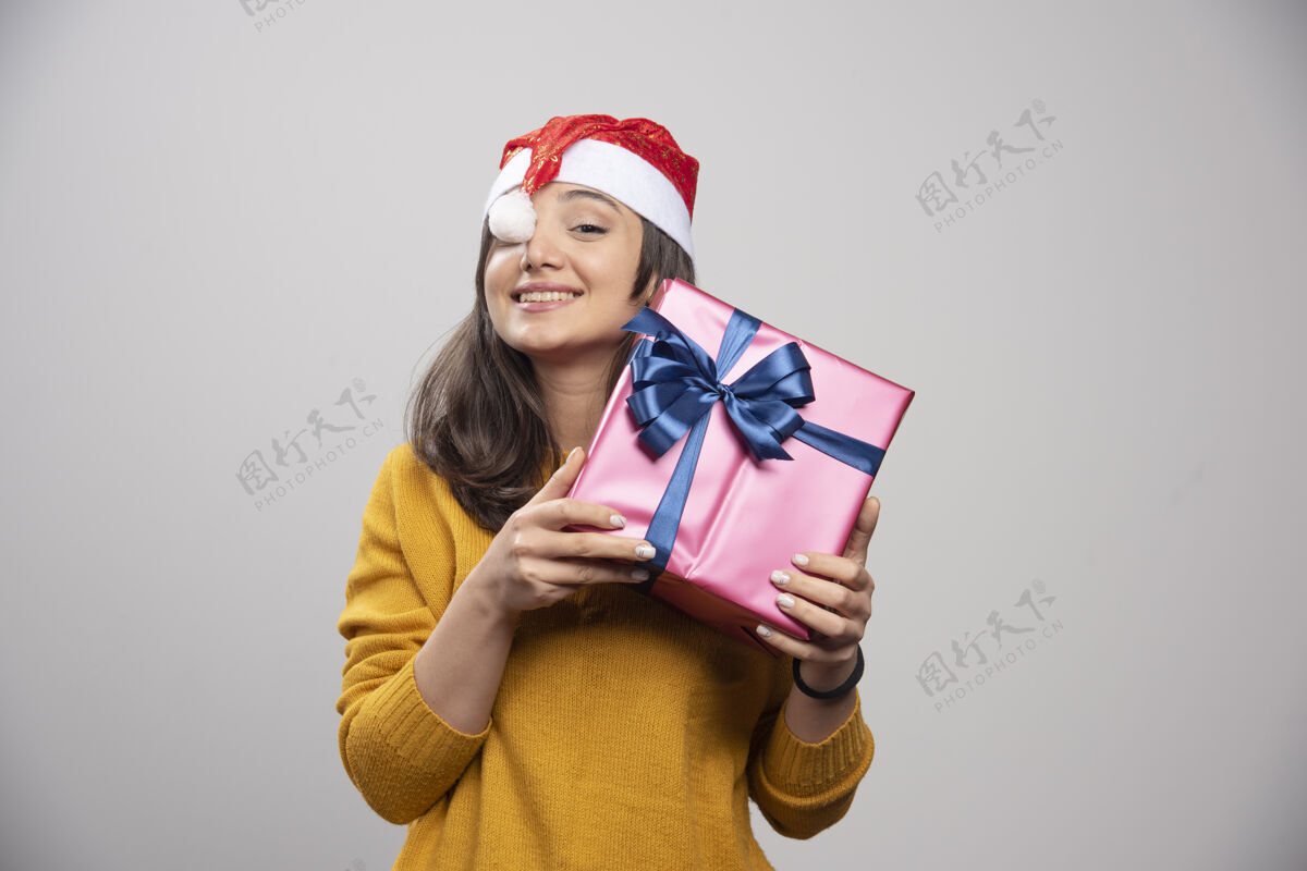 女士带着圣诞礼物的戴着圣诞老人红帽子的微笑女人圣诞老人微笑人