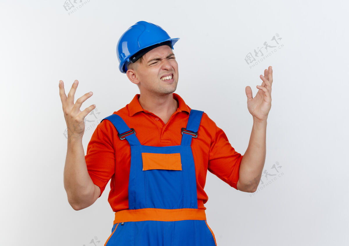 制服困惑地闭上眼睛 年轻的男建筑工人穿着制服 戴着安全帽 双手摊开白色蔓延建筑工人封闭