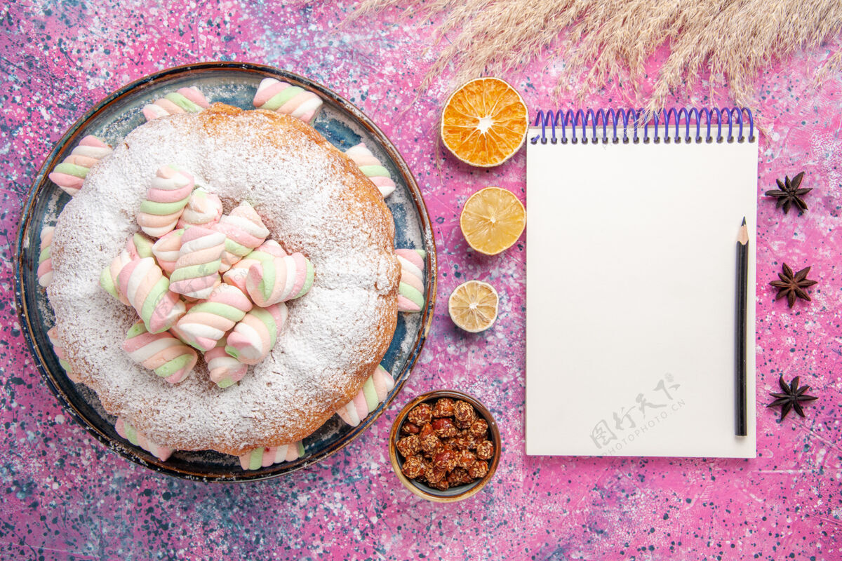 可口糖粉蛋糕的俯视图 粉色表面有甜棉花糖和记事本农产品粉末顶视图