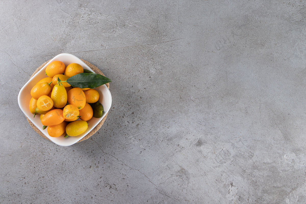 自然金橘水果放在碗里 放在大理石桌上顶视图叶子金橘