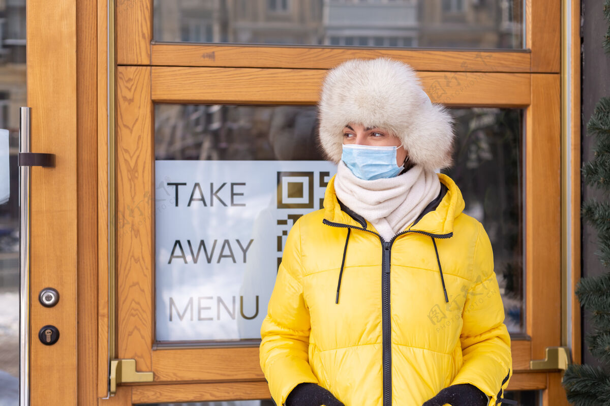 防护口罩在寒冷的冬日 快乐的年轻女子在餐厅门口 刻字 吃外卖工作外卖企业家