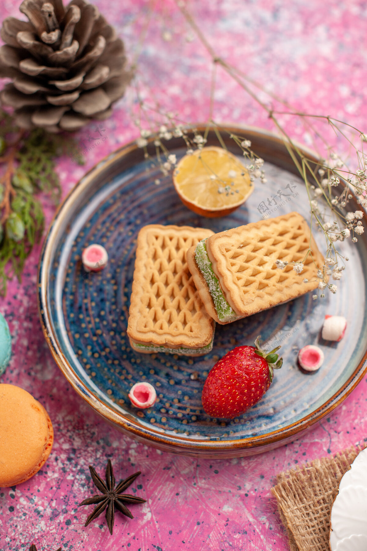 食物粉色表面有美味的华夫饼和法国马卡龙法国草莓顶视图