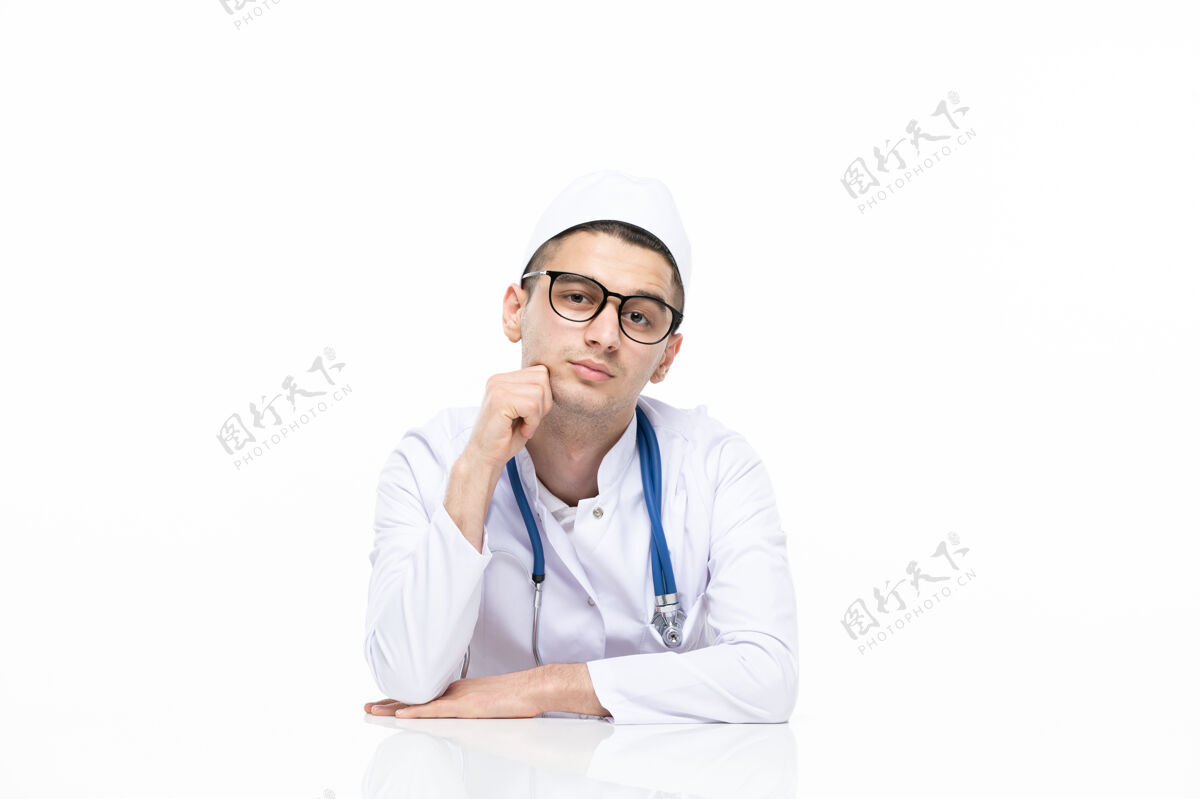 耳机正面图：年轻的医生穿着医疗服坐在桌子后面坐微笑前台