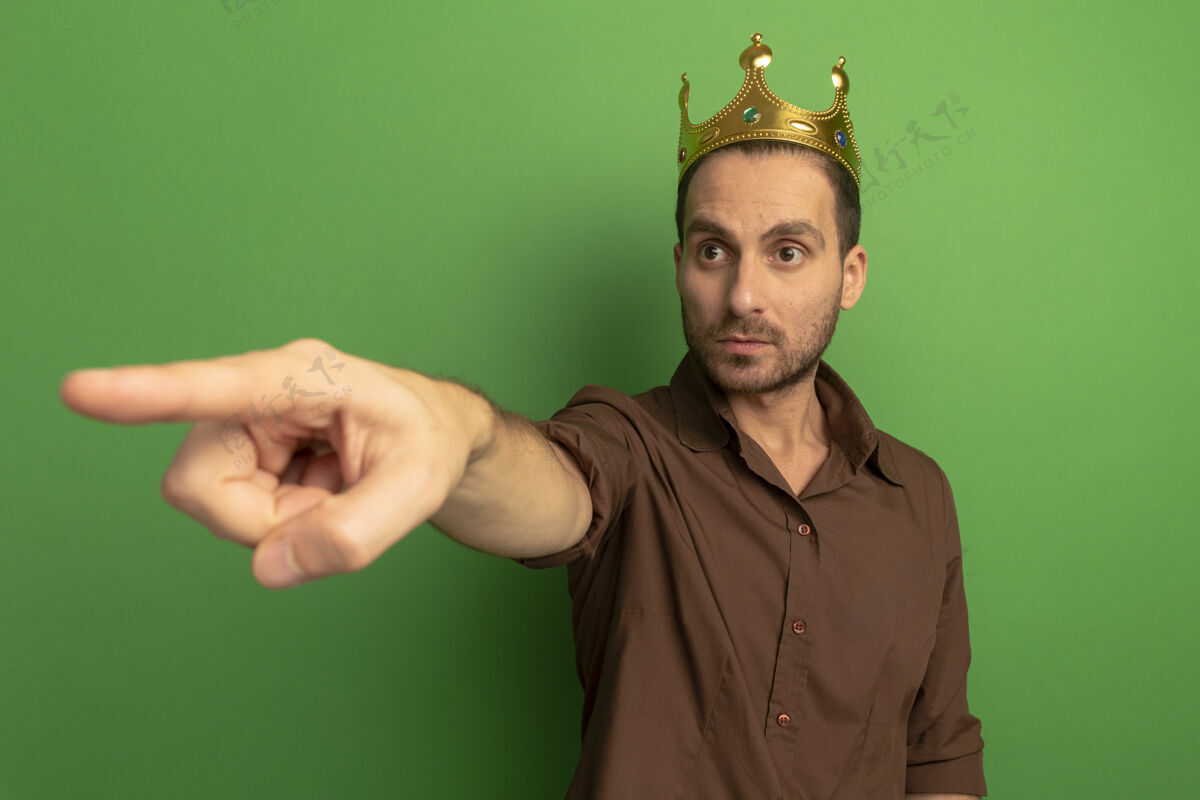 穿着一个戴着皇冠的年轻人望着隔离在绿色墙壁上的一边人人印象